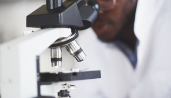 Homem trabalha com um microscópio em um laboratório , representando o estudo de metalografia.